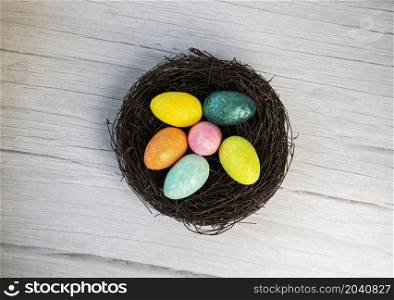 Colorful Easter Egg Nest with Extra White or Gray Wood Board Background for room or space for copy, text, words. A flat lay with square crop, Happy Easter Holliday concept top view. Colorful Easter Egg Nest with Extra White or Gray Wood Board Background for room or space for copy, text, words. A flat lay with square crop, Happy Easter Holliday concept