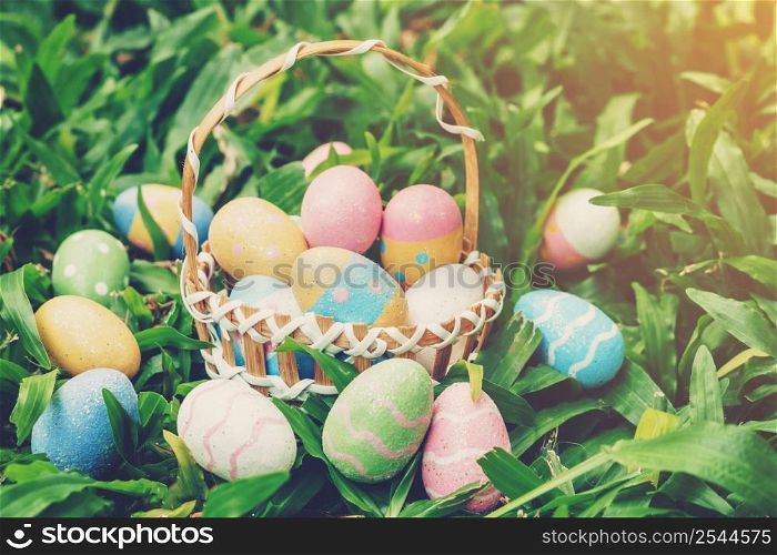 Colorful easter eggs and basket on green grass with sunlight. vintage toned.
