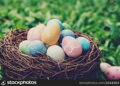 Colorful easter eggs and nest on green grass with sunlight. vintage toned.