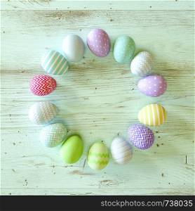 Colorful Easter eggs circle decorated with stripes, flowers and spots in blue, green and yellow on green wood background with copy space for your holiday greeting in square format