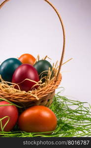 Colorful Easter eggs decorated with butterfly and ladybug in the wicker basket on white background