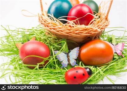 Colorful Easter eggs decorated with butterfly and ladybug in the wicker basket on white background
