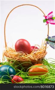 Colorful Easter eggs decorated with butterfly and ladybug in the wicker basket on white background