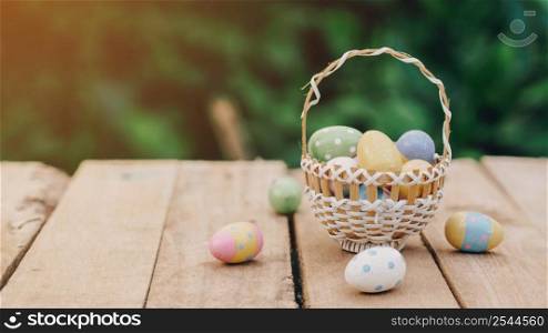 Colorful easter eggs in basket on wooden table with copy space.