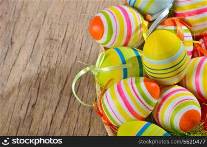 Colorful easter eggs in nest of straw on a wooden table