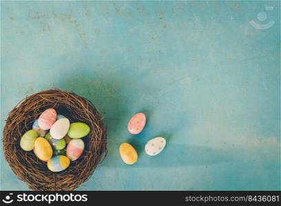 Colorful easter eggs in nest on blue wood background with copy space.