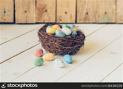 Colorful easter eggs in the nest on wood table background.