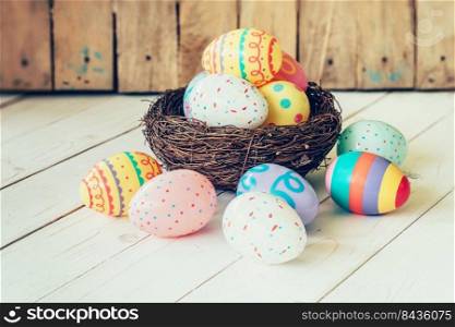 Colorful easter eggs in the nest on wood table background.