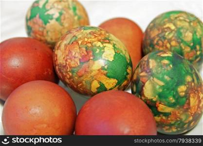 Colorful Easter eggs on white plate placed by heap