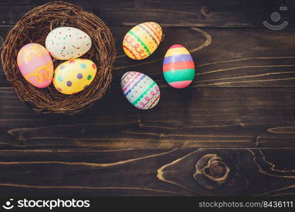 Colorful eggs easter in the nest on wood background with copyspace.
