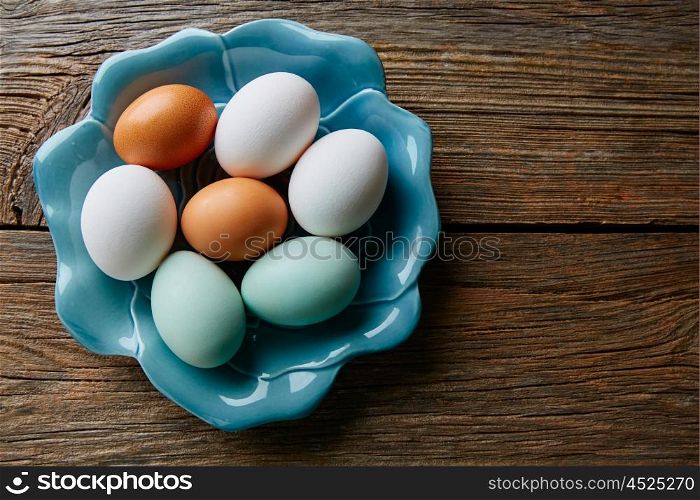 Colorful eggs in white brown and blue colors in a plate on wooden table