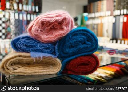 Colorful fabric closeup, textile store, nobody. Shelf with cloth for sewing, clothing patterns choice in shop. Colorful fabric closeup, textile store, nobody