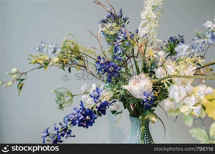 Colorful Fake flowers in a vase on the table colorful green and blue background texture,modern design beauty interior decoration. Colorful Fake flowers in a vase on the table colorful green and blue background texture,modern design