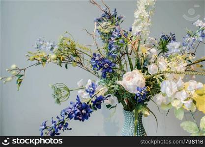 Colorful Fake flowers in a vase on the table colorful green and blue background texture,modern design beauty interior decoration. Colorful Fake flowers in a vase on the table colorful green and blue background texture,modern design