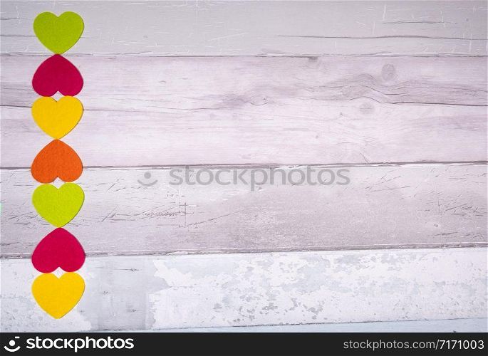 Colorful felt hearts on a background of old wooden planks resembling an old parquet floor. Concept of valentine&rsquo;s day and love in general.. Colorful felt hearts on a background of old wooden planks resembling an old parquet floor. Concept of valentine&rsquo;s day and love in general