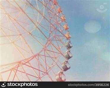 Colorful ferris wheel against blue sky with light leaks and grunge filter effect
