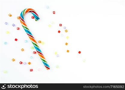Colorful festive Lollipop and small cube letters on white background selective focus top view.. Colorful festive Lollipop and small cube letters on white background selective focus top view