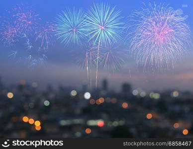 Colorful fireworks on blurred skyscrapers with city bokeh lights illuminated at twilight. Abstract New Year holiday or party background