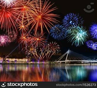 Colorful fireworks reflect from water, beautiful bridge scenery. Colorful fireworks near water
