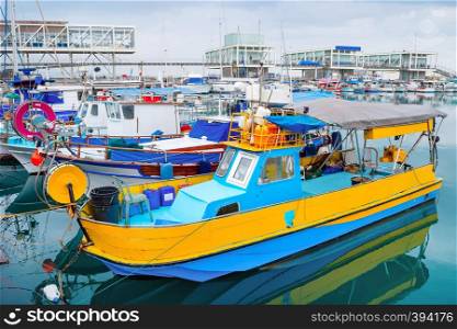 Colorful fishing boats moored in Limassol marina with restaurants on pier, Cyprus