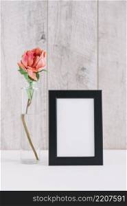 colorful flower vase near blank picture frame table
