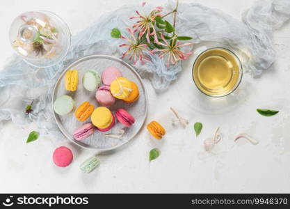 Colorful french macaroon cakes. Macaroons with jasmine flowers and tea on white table background. Selective focus