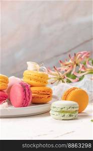 Colorful french macaroon cakes. Macaroons with jasmine flowers on white table background. Selective focus