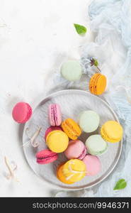 Colorful french macaroon cakes. Macaroons with jasmine flowers on white table background. Selective focus