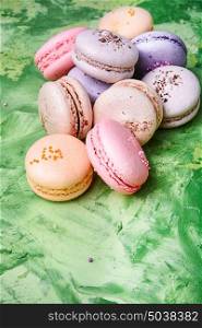 Colorful French macaroons. French macaroons dessert on a green background