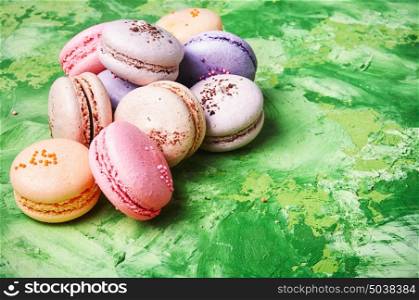 Colorful French macaroons. French macaroons dessert on a green background