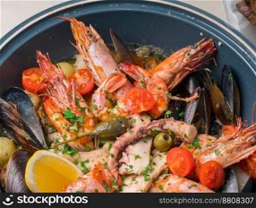 Colorful fresh seafood with vegetables and spices on blue plate in restaurant. Close up. Colorful fresh seafood with vegetables and spices on blue plate in restaurant