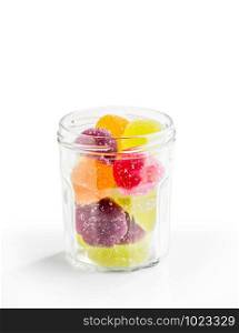 Colorful fruit jelly in open glass jar, on white background