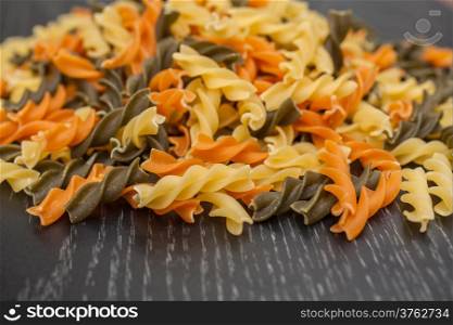 Colorful Fusilli spreading on black wood table background