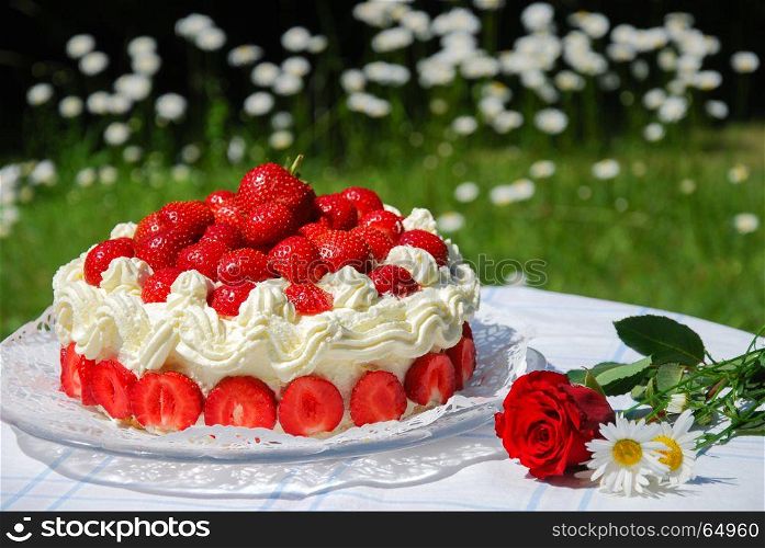 Colorful garden table with strawberry cake and summer flowes