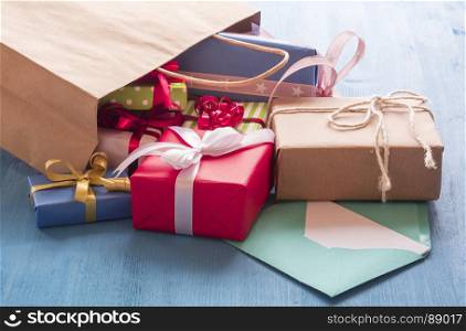 Colorful gift boxes coming out on a blue wooden table from a paper shopping bag