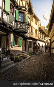 colorful halftimbered houses along a narrow street with cobblestones in the medieval town of Eguisheim, Alsace Region, France
