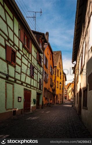 colorful halftimbered houses along a narrow street with cobblestones in the medieval town of Riquewihr, Alsace Region, France