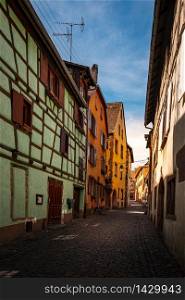 colorful halftimbered houses along a narrow street with cobblestones in the medieval town of Riquewihr, Alsace Region, France
