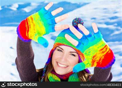 Colorful hands up of a happy smiling girl wearing winter clothes, beautiful female close up portrait, young pretty woman face with natural snow background, winter fun outdoor, happy people concept