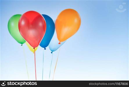 Colorful helium balloons for birthday and celebrations isolated at blue sky with copy space for free text. Colorful balloons for birthday and celebrations isolated at blue sky