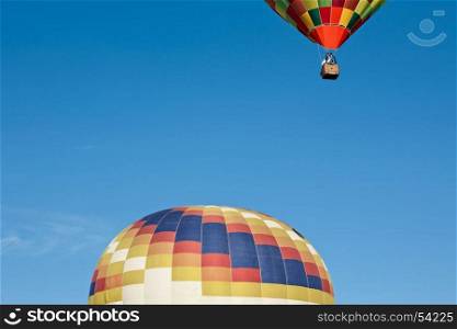 Colorful hot-air balloon ready to get up in flight and another already in flight against a blue sky. Colorful hot-air balloon ready to get up in flight and another already in flight