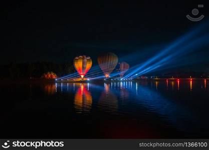 Colorful hot air balloons flying over river on night festival