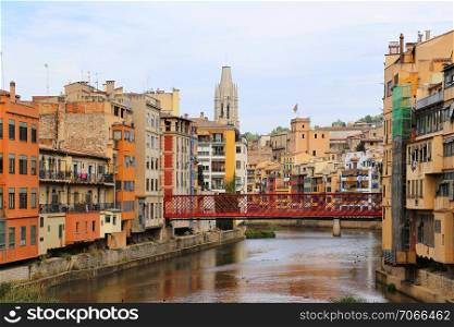 Colorful houses and Eiffel bridge (Pont de les Peixateries Velles) reflected in water river Onyar, Basilica of Sant Feliu in Girona, Catalonia, Spain