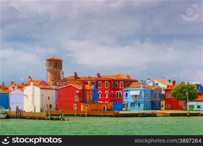 Colorful houses and tower on the famous island Burano, view from the sea, Venice, Italy