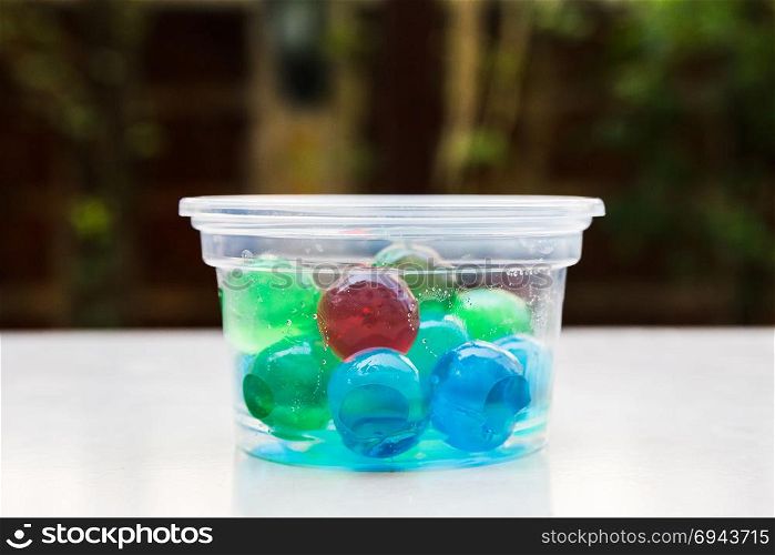 Colorful jelly ball in plastic cup on white floor.