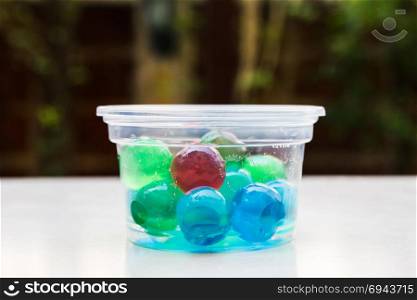 Colorful jelly ball in plastic cup on white floor.