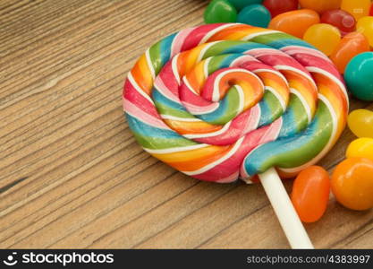Colorful jelly beans and lollipop close to wallpaper
