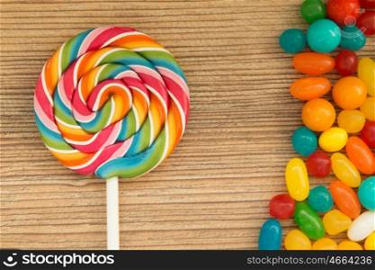 Colorful jelly beans and lollipop close to wallpaper