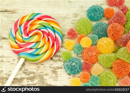 Colorful jelly beans and lollypop close to wallpaper