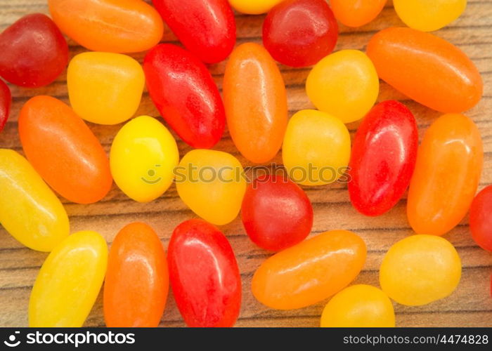 Colorful jelly beans of different sizes close to wallpaper